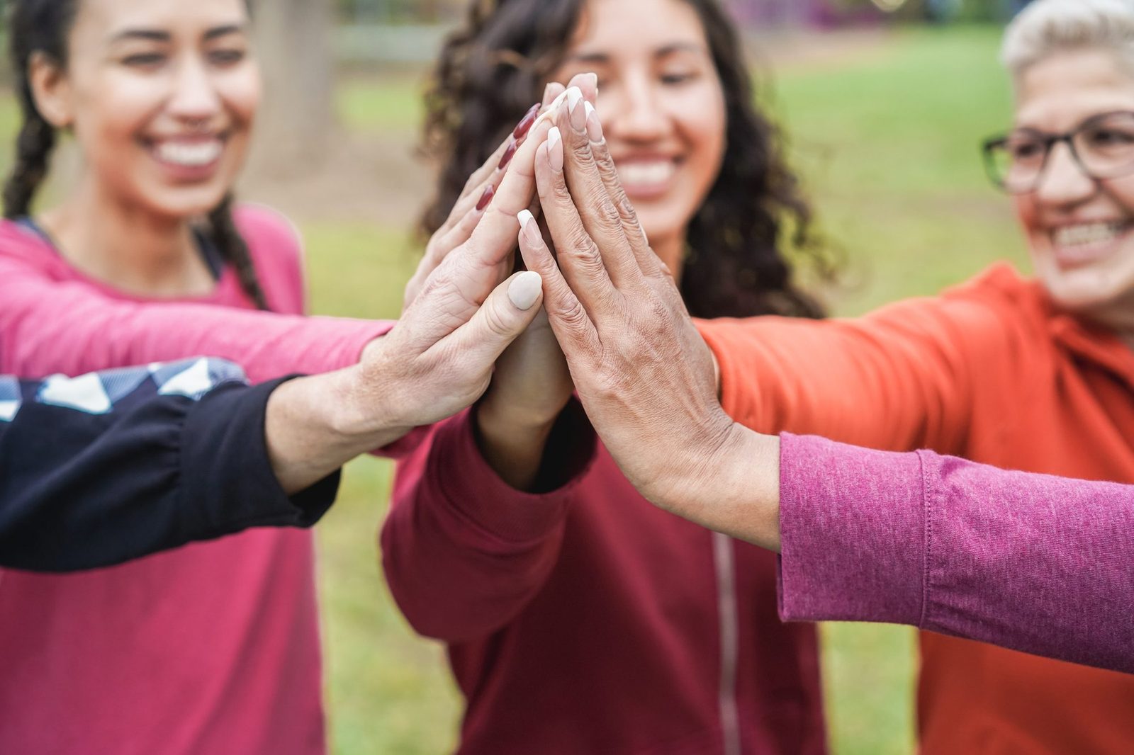 Women of different backgrounds stacking their hands together in support