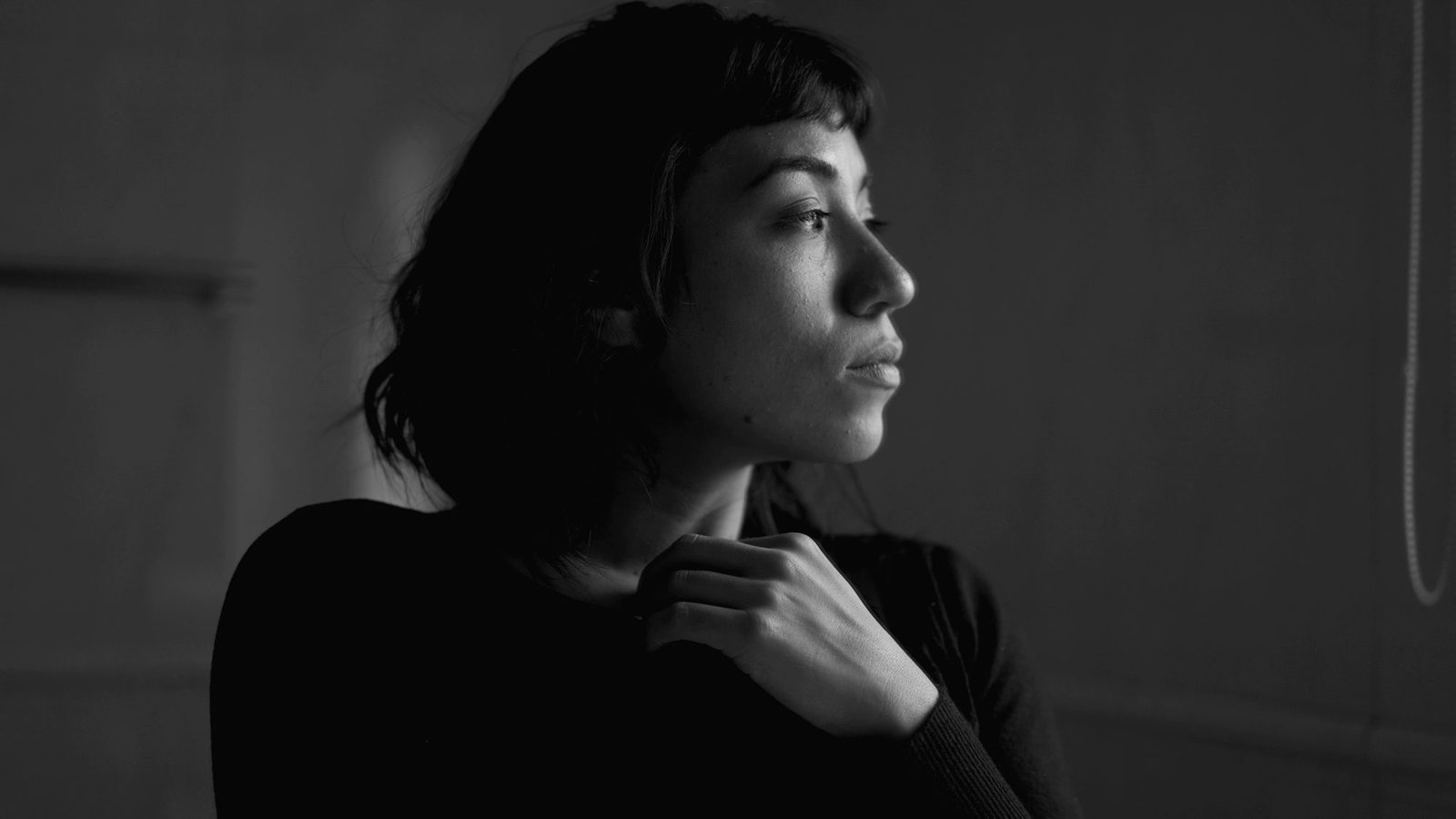 A contemplative young woman standing by a window